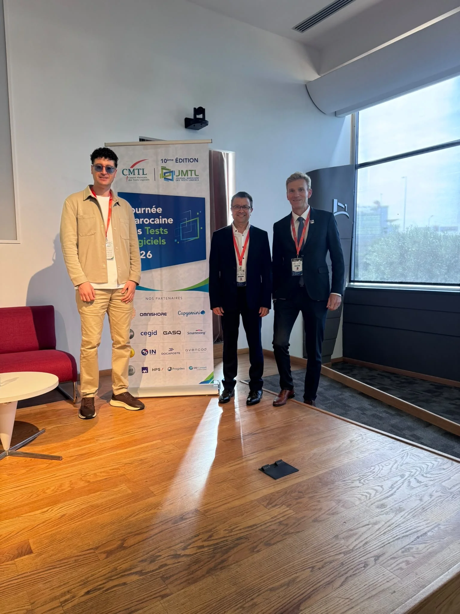 Trois participants posent devant une bannière CMTL et JMTL 2026, dans la salle de conférence.