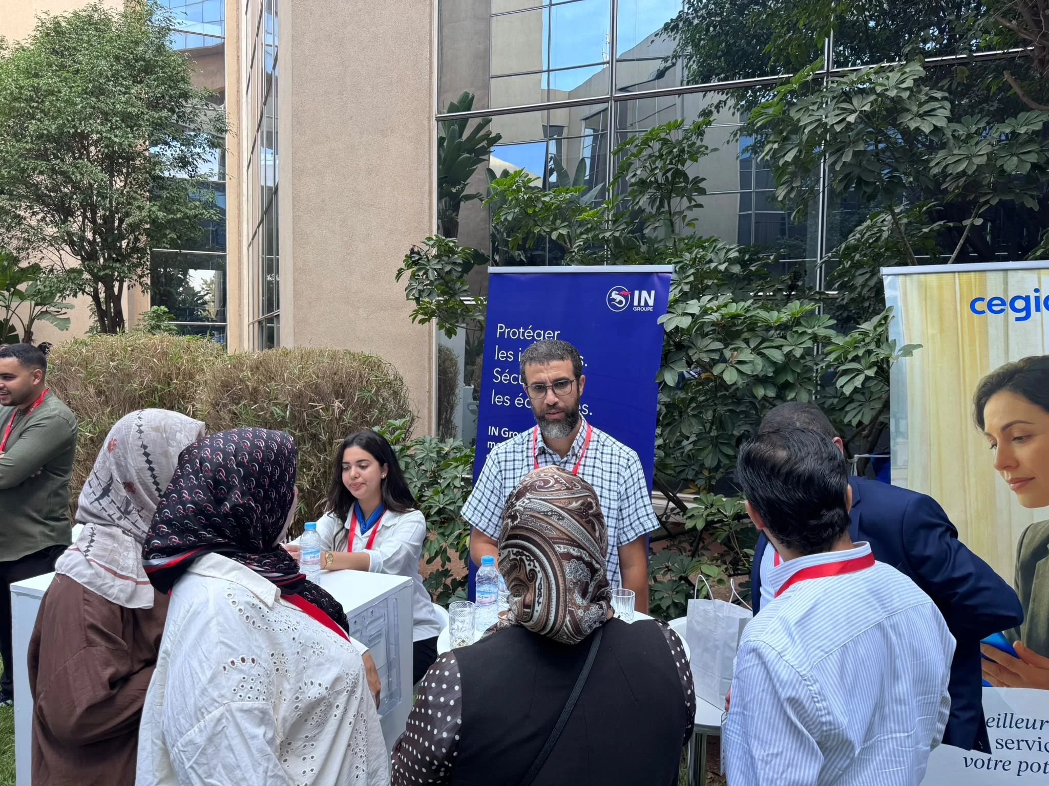 Un groupe de participants discute autour d’un stand, près des bannières IN Groupe et Cegid.